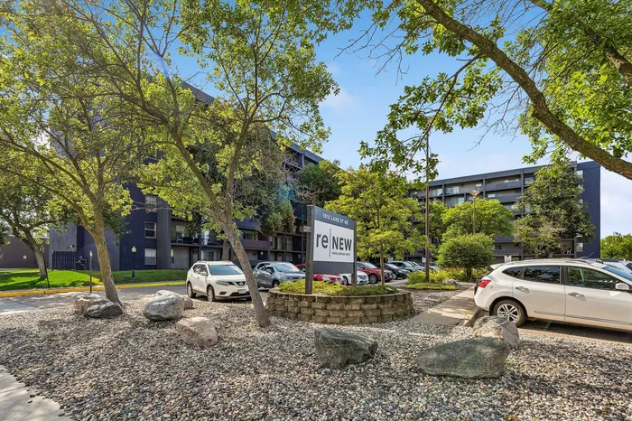 Charming apartment complex with lush greenery, ample parking, and modern design.