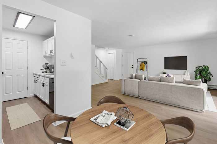 Modern open-plan living space featuring a cozy living area with a large TV, elegant dining table, and a sleek kitchen corner; ideal for comfortable and stylish living.