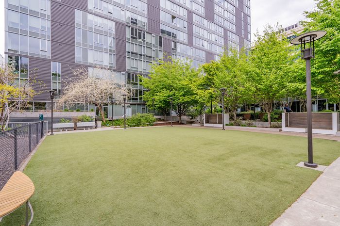Modern apartment complex with a lush, green courtyard featuring trees and well-maintained landscaping, offering serene outdoor space.
