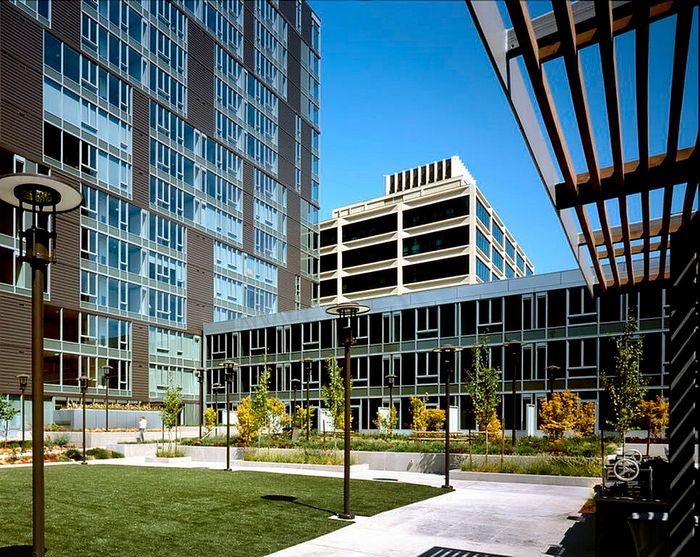 Modern urban apartment complex with sleek glass windows and a beautifully landscaped courtyard.