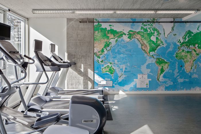 Contemporary fitness center with treadmills and an expansive world map, offering a vibrant workout space with natural light.