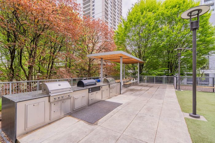 Chic outdoor terrace featuring modern grills, ample seating area, and lush green surroundings for perfect entertaining.