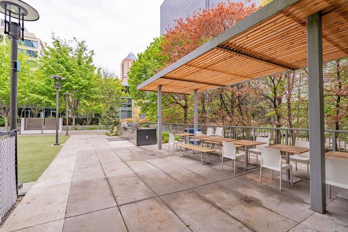 Inviting outdoor patio with modern pergola and ample seating, surrounded by lush greenery and barbecue grills.