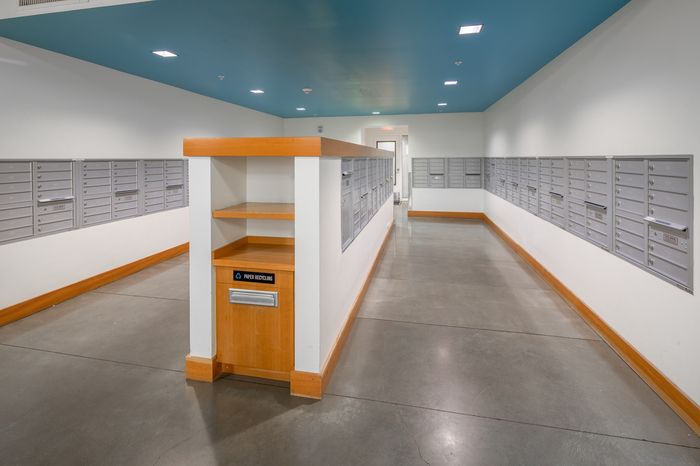 Bright and modern mailroom featuring sleek mailboxes and an eco-friendly paper recycling station.