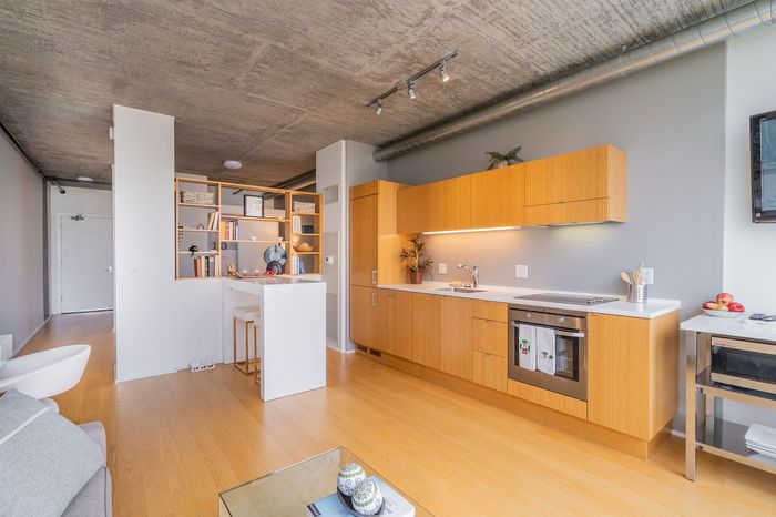 Modern open-plan kitchen with sleek cabinetry, light wood floors, and stylish shelving, perfect for contemporary living.