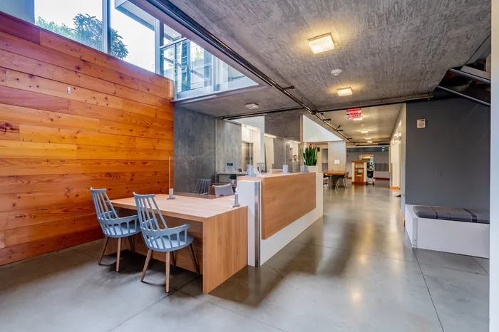 Modern apartment lobby with sleek wooden accents and stylish metal chairs, featuring a spacious and welcoming reception area.