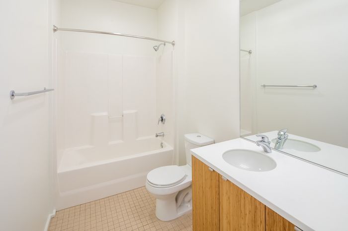 Bright and modern bathroom featuring a sleek shower-tub combo, elegant vanity with ample storage, and contemporary fixtures.