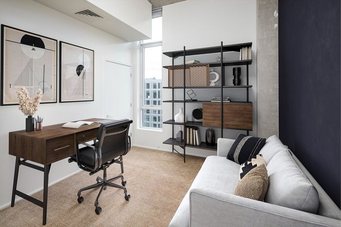Modern home office with sleek wooden desk, ergonomic chair, and stylish art in a bright, airy room.