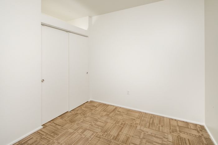 Bright and inviting room with crisp white walls and plush beige carpet, ideal for a modern touch.