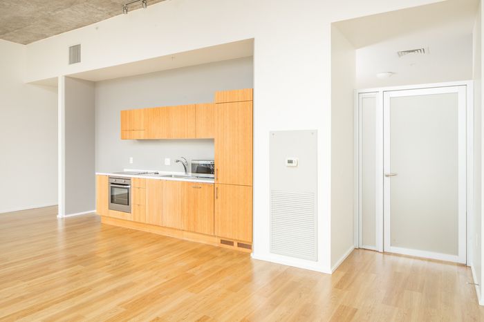Spacious modern kitchen with sleek wooden cabinetry and integrated appliances in an elegant open-plan apartment.