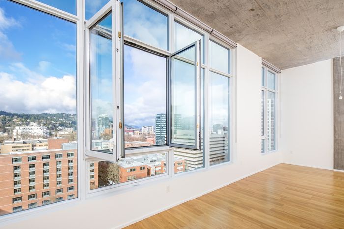 Bright city apartment featuring tall windows with stunning panoramic views and elegant hardwood floors.