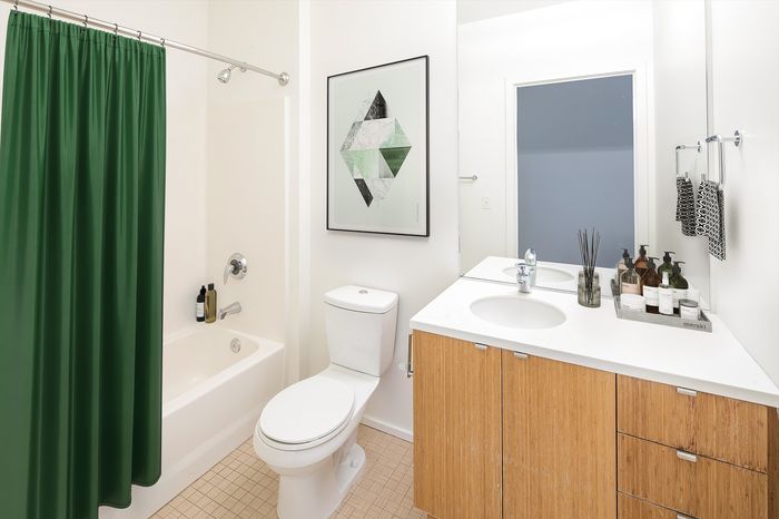 Modern bathroom with elegant design, featuring a green shower curtain, stylish vanity, and contemporary artwork.