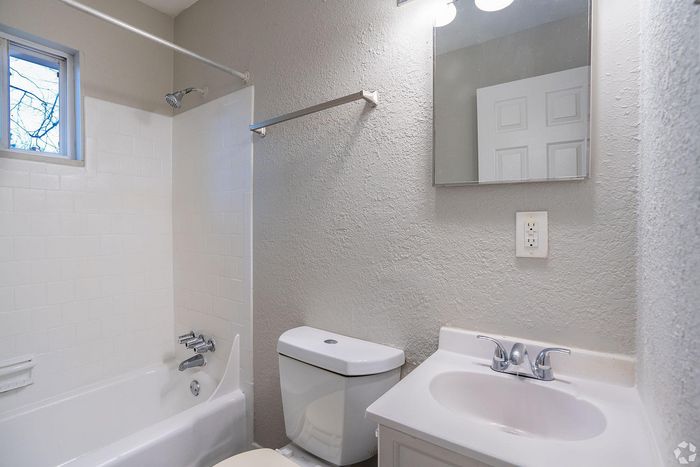 Bright and modern bathroom featuring elegant fixtures, crisp white tiles, and ample natural light from a small window.