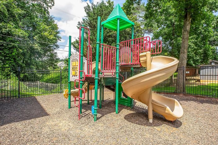 Inviting playground with vibrant slides and climbing equipment surrounded by lush greenery, perfect for outdoor family fun.