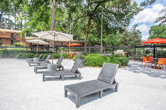 Inviting outdoor space with modern lounge chairs, vibrant umbrellas, and lush greenery, perfect for relaxation and social gatherings.