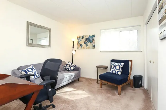 Bright and inviting living space featuring a modern gray sofa, stylish blue accents, and elegant wall art, perfect for relaxation.