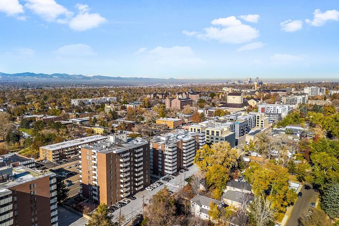 Vibrant aerial view of a thriving urban neighborhood surrounded by lush greenery and a picturesque mountain backdrop.