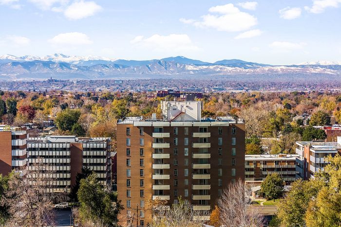 Stunning cityscape with scenic mountain views, featuring modern apartment buildings nestled amidst vibrant autumn foliage.