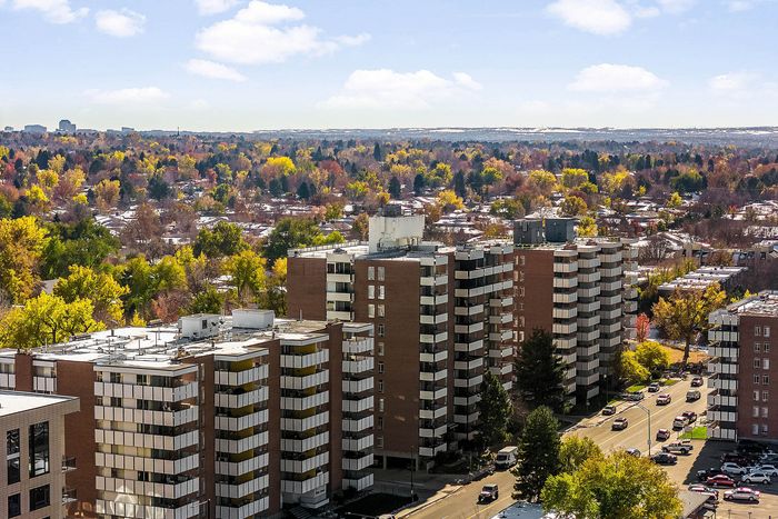 Captivating aerial view of modern apartment buildings surrounded by vibrant autumn foliage, offering urban living with a natural backdrop.