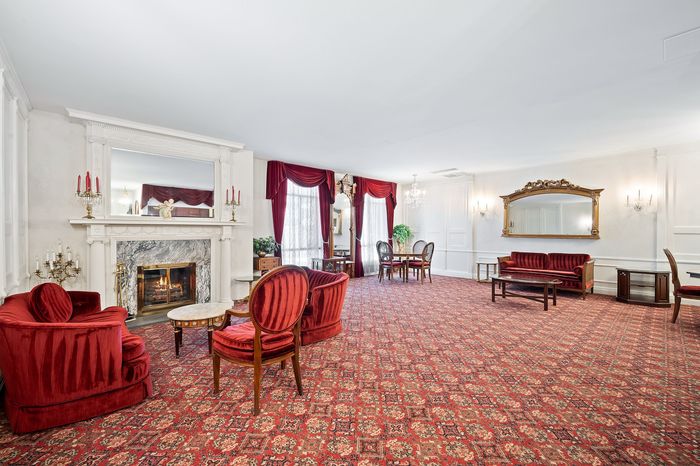 Elegant living room featuring luxurious red velvet seating, ornate fireplace, and grand mirror, exuding classic sophistication.