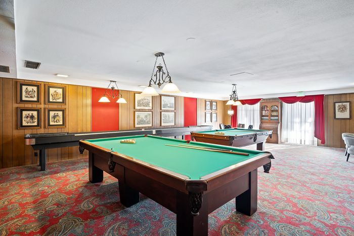 Charming recreation room featuring billiard tables, elegant lighting, and cozy seating, ideal for entertainment and relaxation.