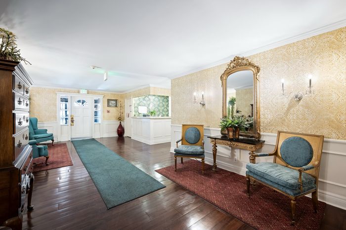 Elegant apartment lobby featuring classic decor, with luxurious seating, ornate mirror, and charming floral accents.