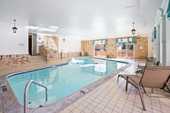 Inviting indoor pool area with elegant brick walls, ample seating, and large windows offering a serene ambiance.