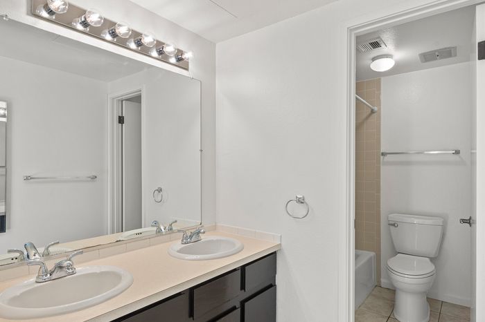 Modern bathroom featuring dual sinks, chic lighting, and a pristine shower area.
