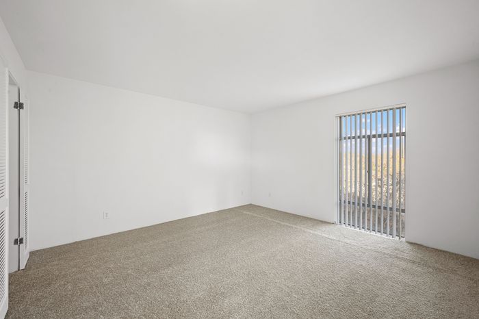 Bright and airy bedroom with plush carpeting and large window offering serene views, perfect for creating a cozy retreat.