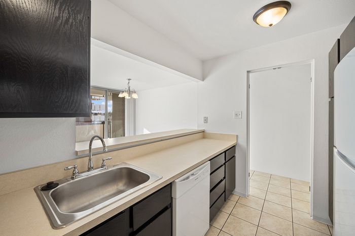 Bright and inviting modern kitchen with sleek black cabinets, spacious countertops, and a cozy dining area view.