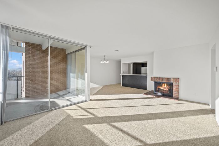 Bright and airy living room with a cozy fireplace, open space, and sliding glass doors leading to a balcony with scenic views.