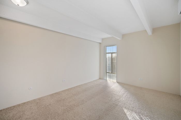 Bright and spacious room with plush carpeting and a large window, ideal for a cozy retreat.
