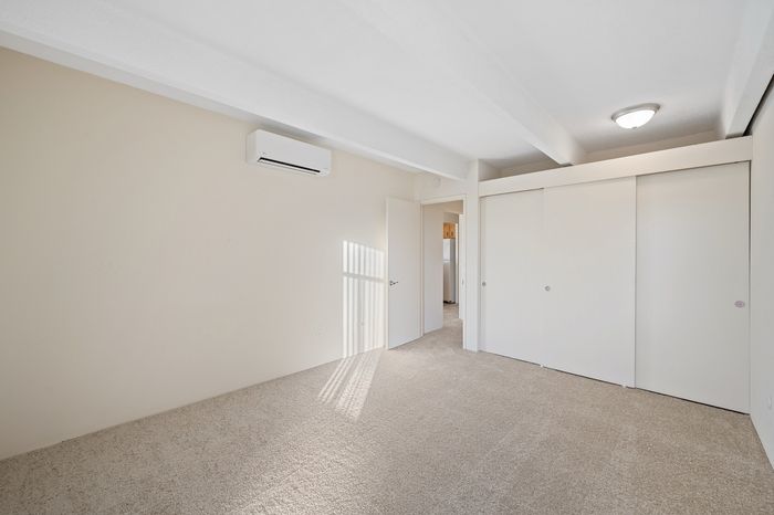 Spacious, sunlit bedroom with plush carpeting and modern air conditioning.