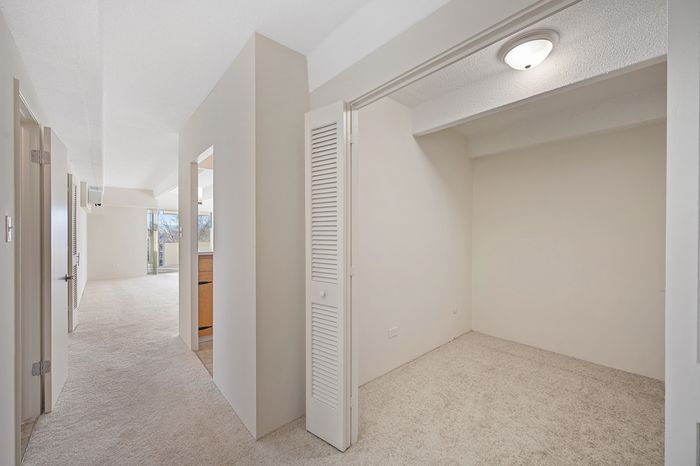 Bright and inviting hallway with plush carpeting leading to a spacious living area and cozy nook, perfect for personalization.