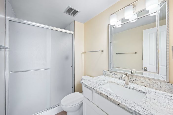 Bright, modern bathroom with elegant granite countertop, sleek fixtures, and a spacious shower enclosure.