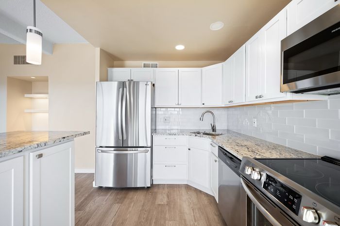 Modern kitchen with sleek stainless steel appliances, elegant granite countertops, and pristine white cabinetry.
