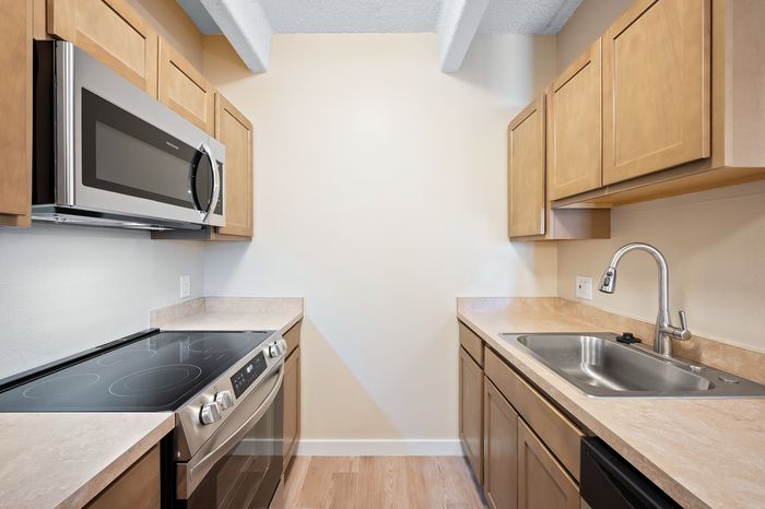 Sleek modern kitchen with stainless steel appliances, warm wood cabinetry, and elegant countertops.