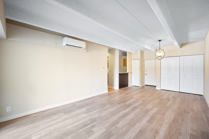 Bright open-concept living area with modern wood flooring, elegant light fixture, and ample natural light for a welcoming home.
