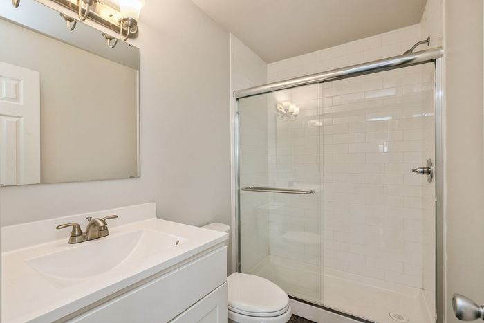 Modern bathroom featuring a sleek vanity with elegant fixtures, a large mirror, and a stylish glass-enclosed shower.