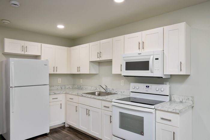 Modern kitchen with sleek white cabinets, marble countertops, and high-quality appliances.