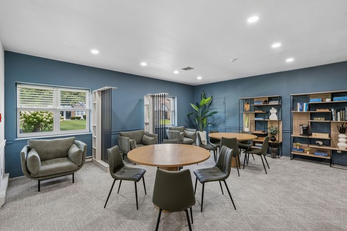 Modern community room with stylish round tables, comfortable seating, and vibrant blue walls, perfect for social gatherings and relaxation.