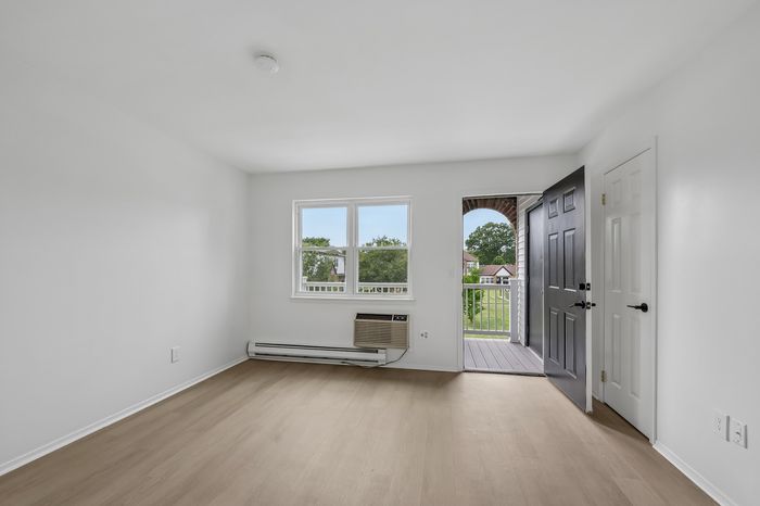 Bright and airy room with large window and door leading to a private balcony, showcasing serene green views.