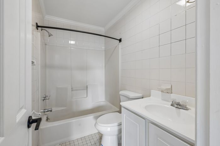 Bright and inviting bathroom featuring modern fixtures, elegant tile work, and a spacious bathtub.