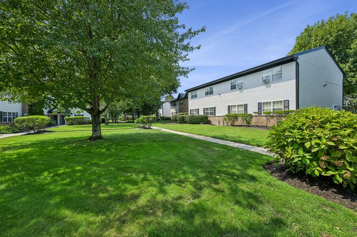 Beautiful apartment complex with manicured lawns and lush greenery, offering a serene and inviting atmosphere.