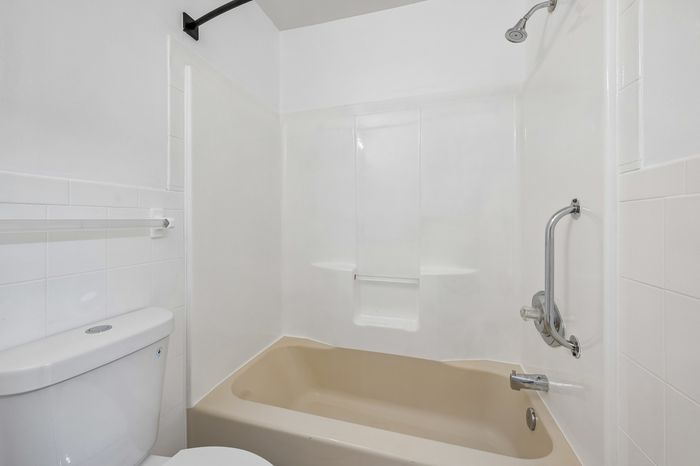 Elegant bathroom with a modern shower-tub combo and sleek white tiles for a luxurious touch.
