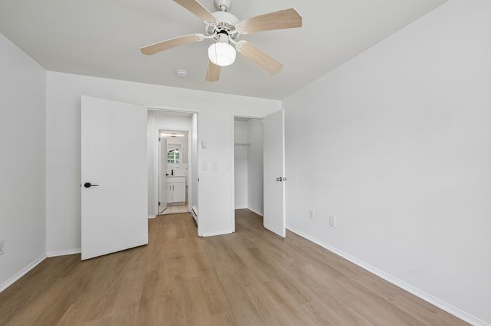 Bright and airy bedroom with modern ceiling fan, hardwood floors, and convenient ensuite bathroom access.