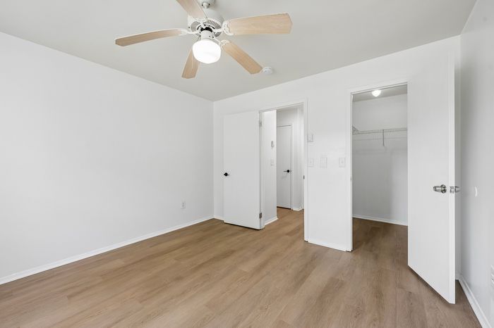 Bright and airy bedroom with elegant wood flooring, spacious closet, and modern ceiling fan.