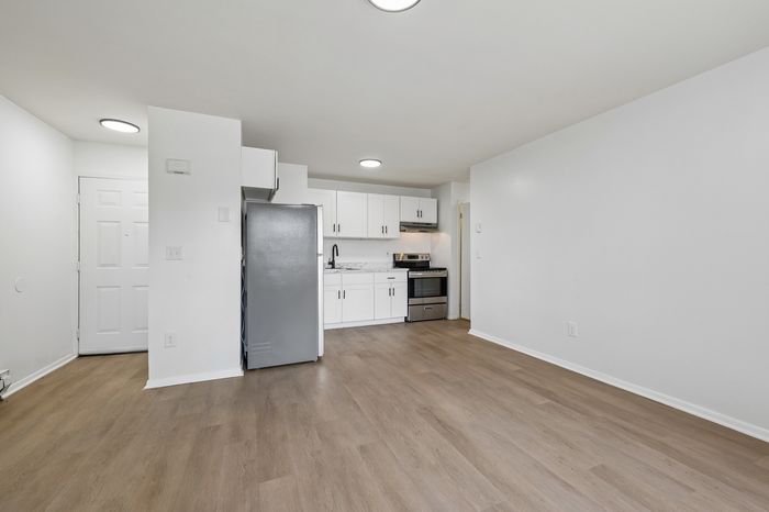 Bright modern kitchen with sleek stainless steel appliances, elegant white cabinetry, and spacious wood flooring.