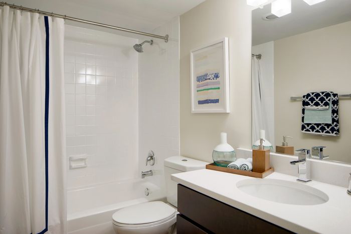 Modern bathroom with elegant decor featuring a sleek vanity, framed artwork, and a luxurious shower-tub combination.