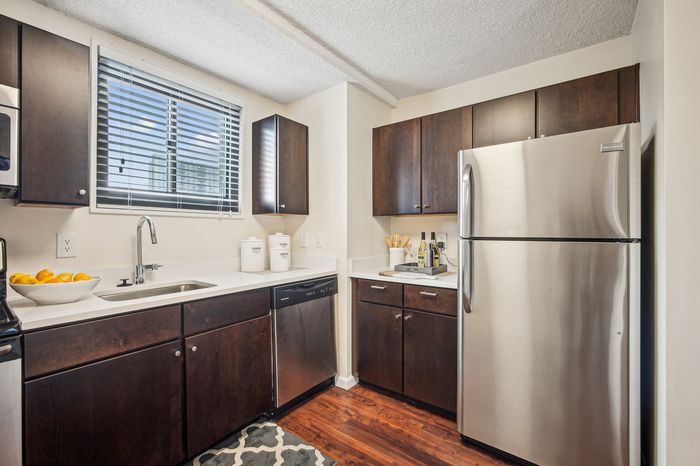 Modern kitchen with sleek stainless steel appliances, rich dark wood cabinetry, and a bright window view, creating an inviting cooking space.